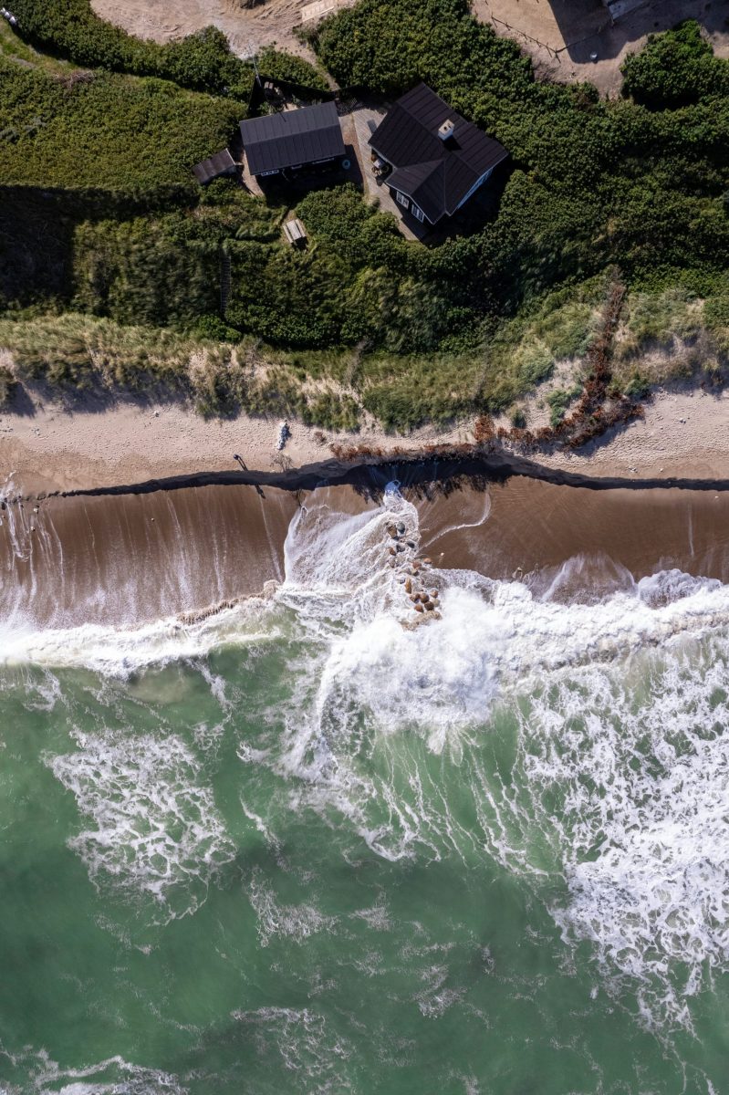 Familie spielt Ball vor einem Ferienhaus in den Dünen an der Küste
