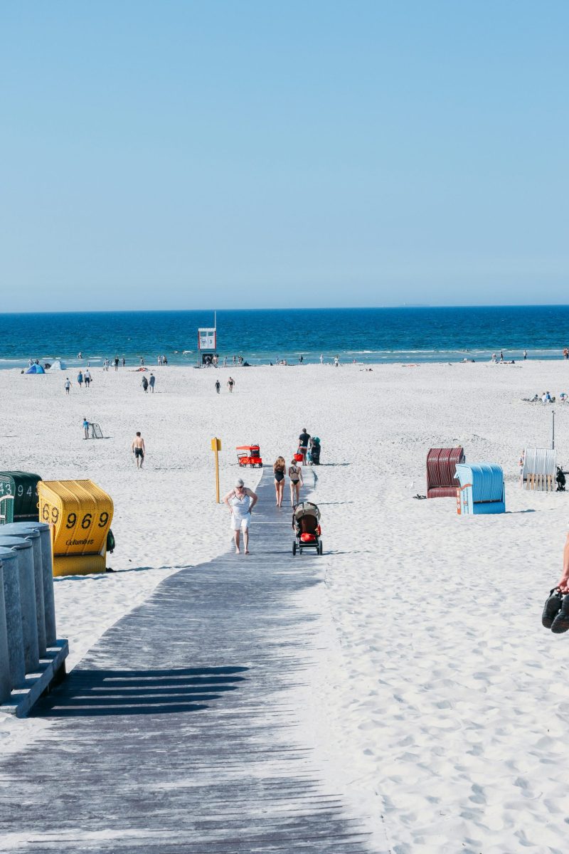 Familie fährt Fahrrad an einem Seeufer mit Bergen im Hintergrund