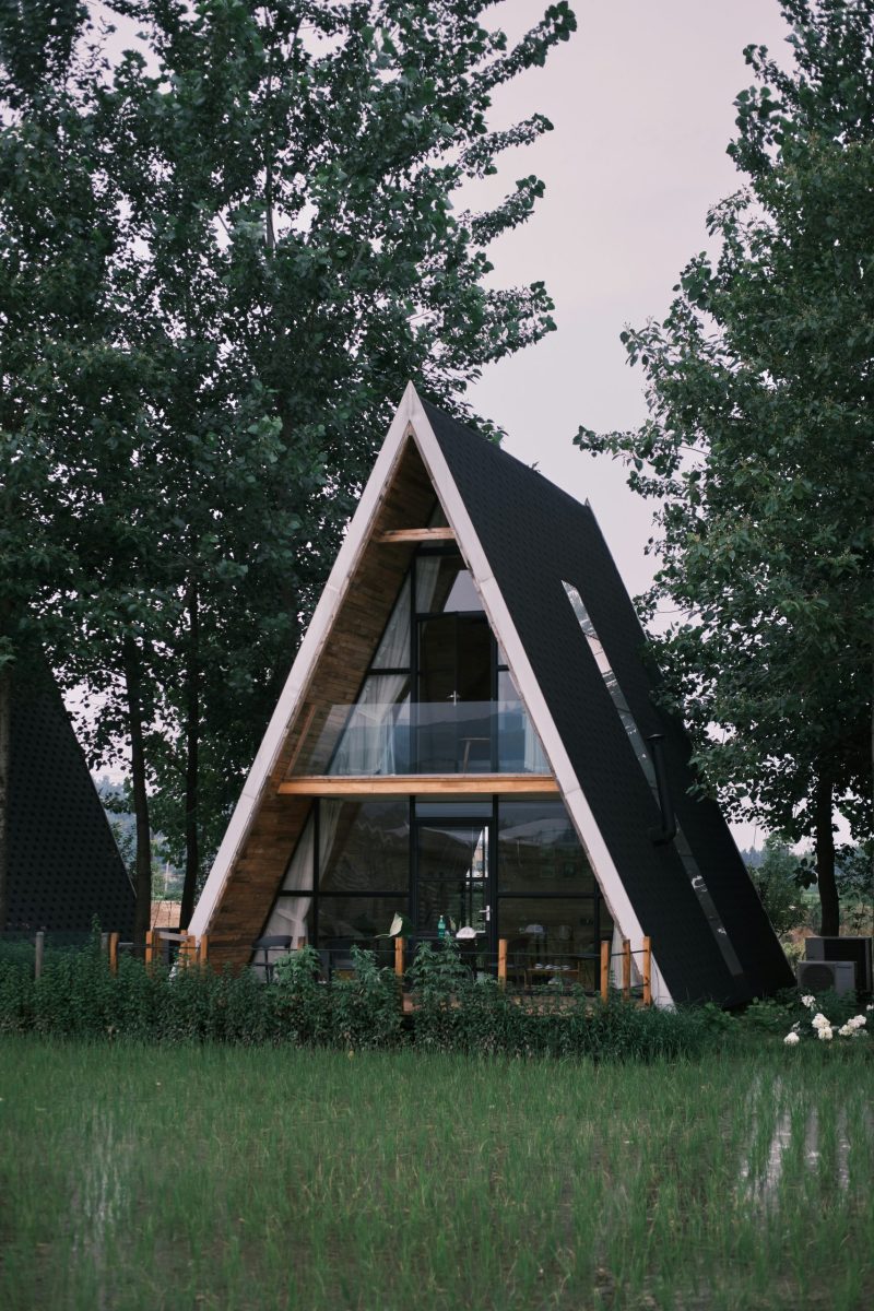Familie mit Kindern spielt vor einer Berghütte auf einer grünen Wiese in den Bergen