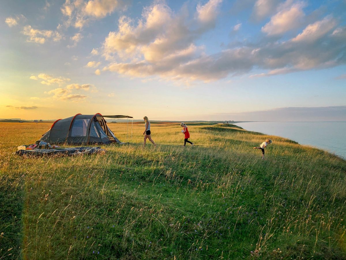 Wohnwagen auf grünem Campingplatz am See in Bayern mit Bergen im Hintergrund