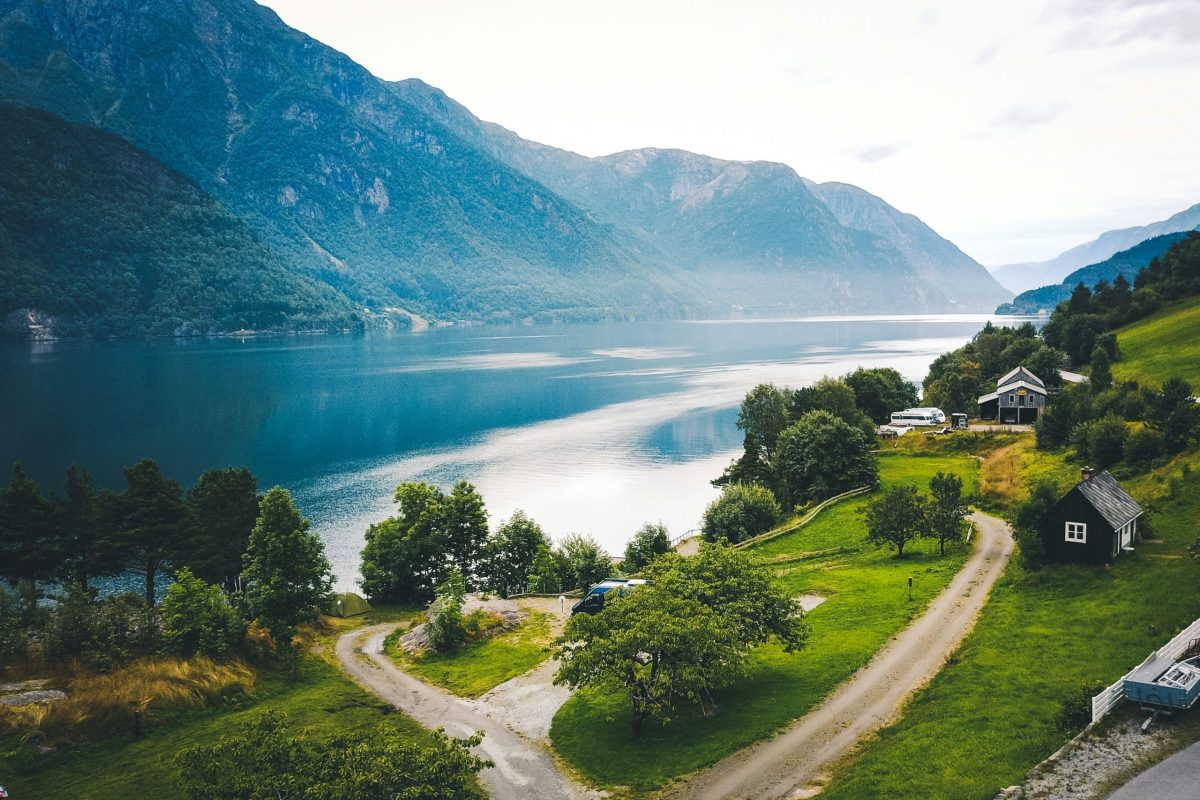 Rotes Ferienhaus am Fjord mit Bootssteg und Bergen im Hintergrund